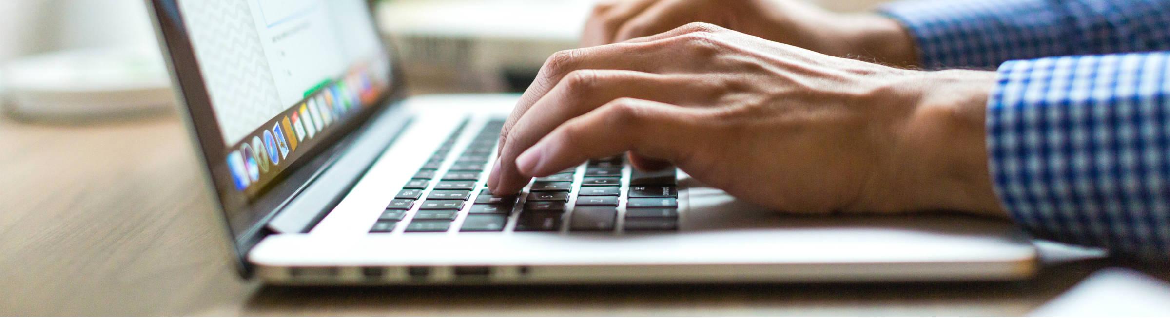 Un homme écrit sur son ordinateur portable